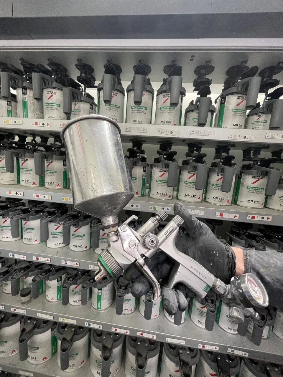 Paint spray gun in front of paint mixing supplies.