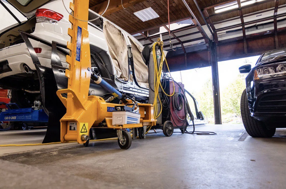 Yellow structural/frame repair equipment and vehicle in workshop.