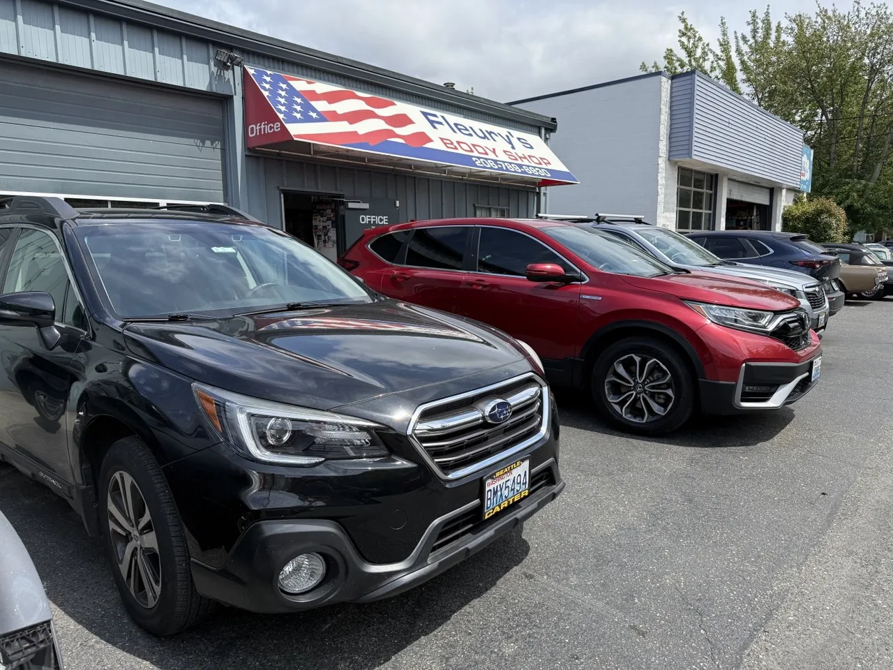 Ballard body shop exterior, signage and parked vehicles.