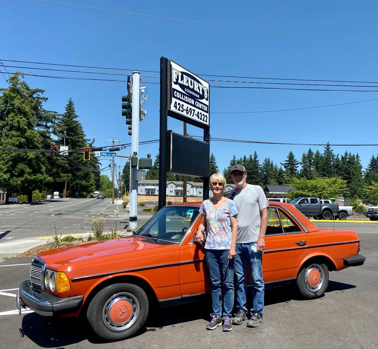 Two adults beside an orange classic Mercedes-Benz outside Lynnwood.