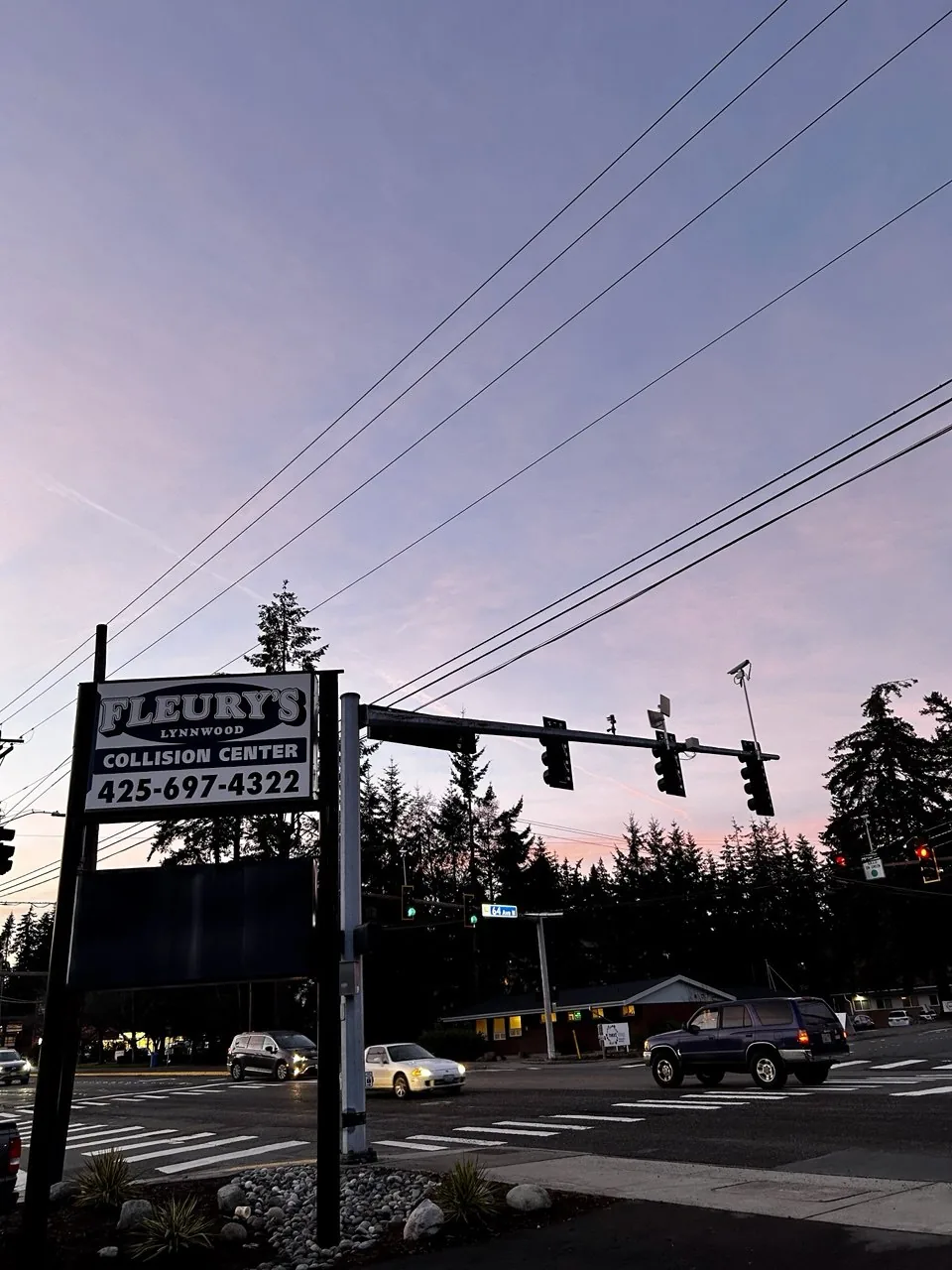Lynnwood roadside sign at dusk beside traffic signals.
