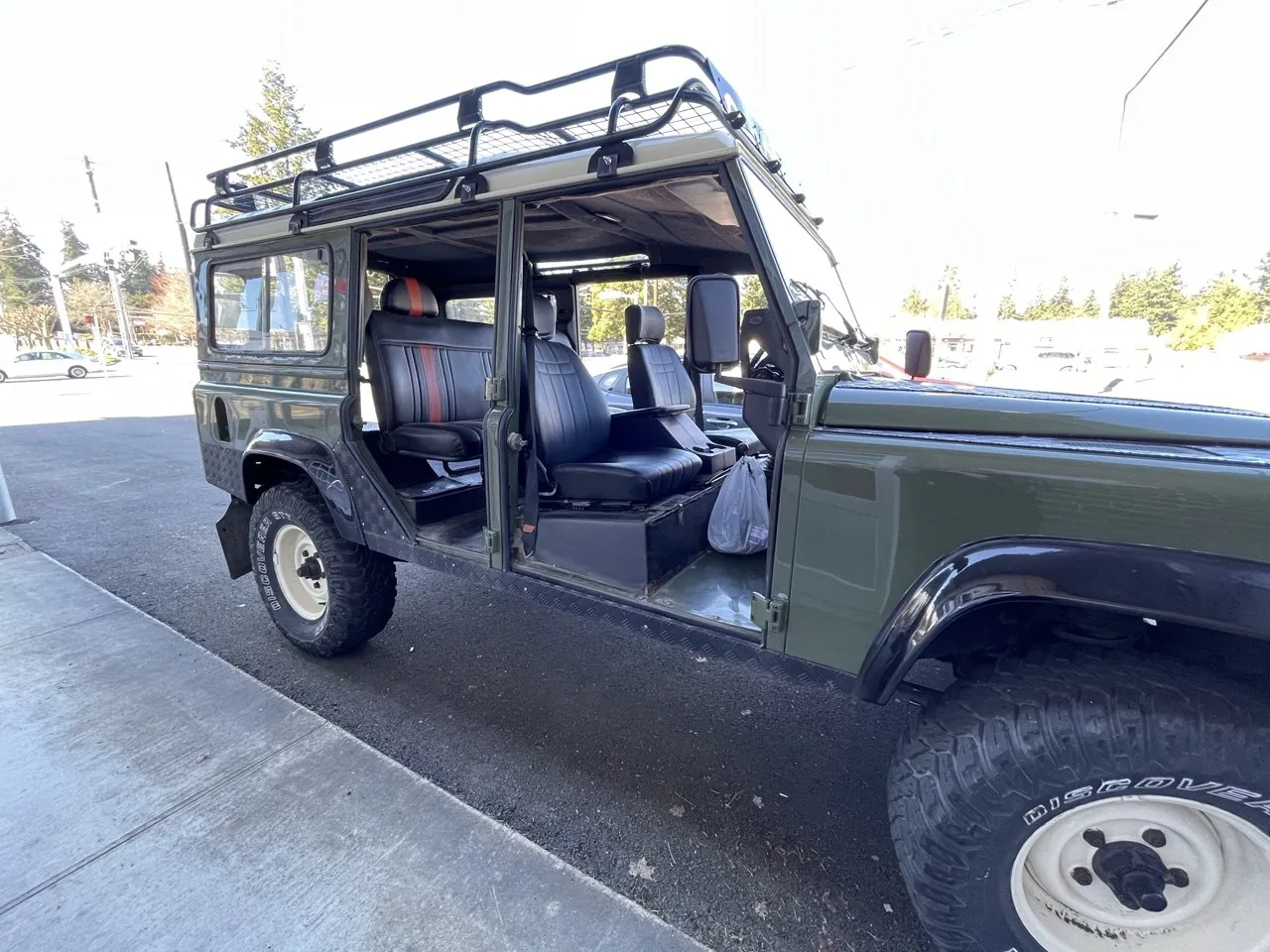 Green Land Rover with doors removed/open outdoors.