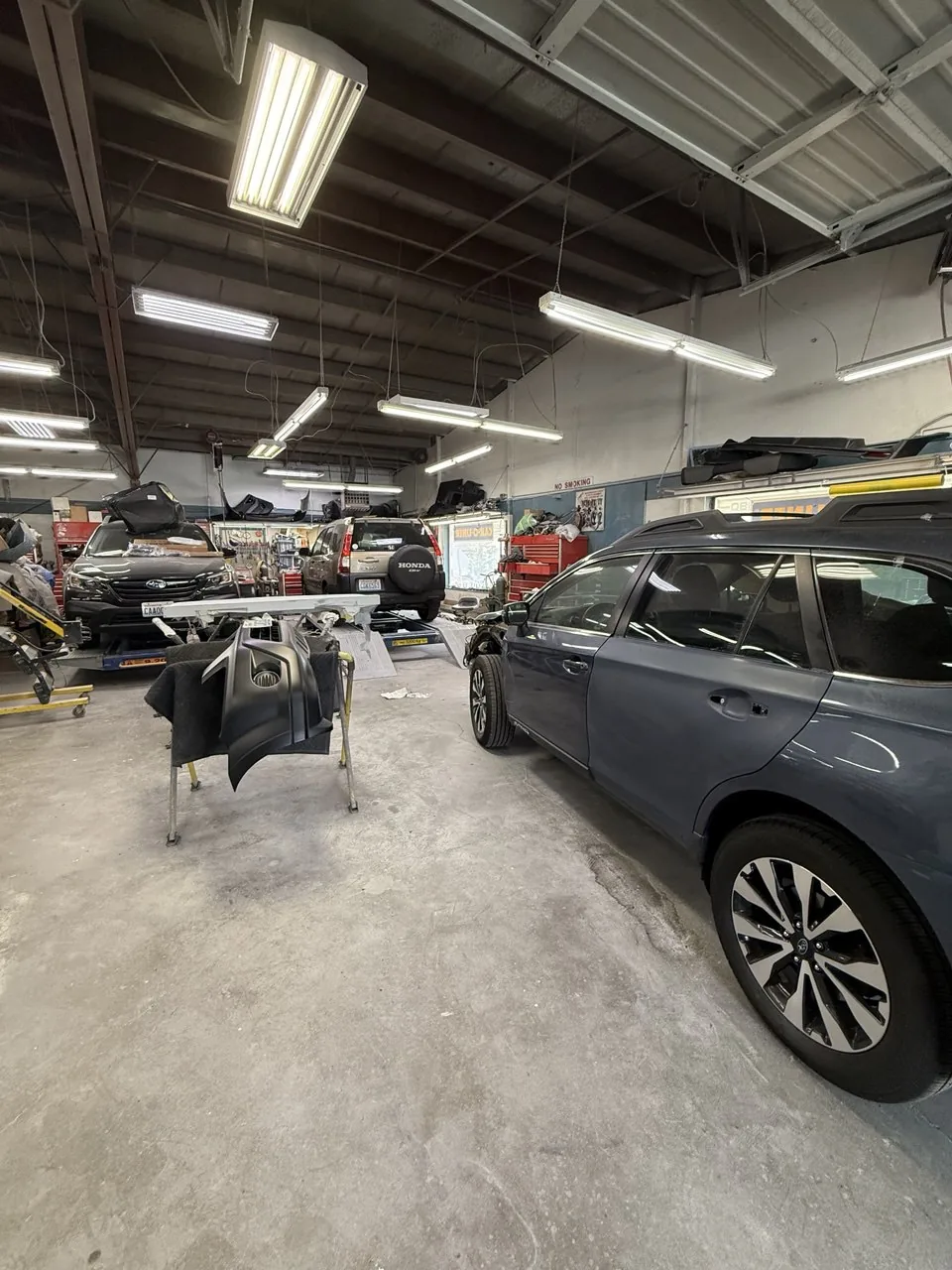 Tall wide-angle view of busy shop interior and repair vehicles.