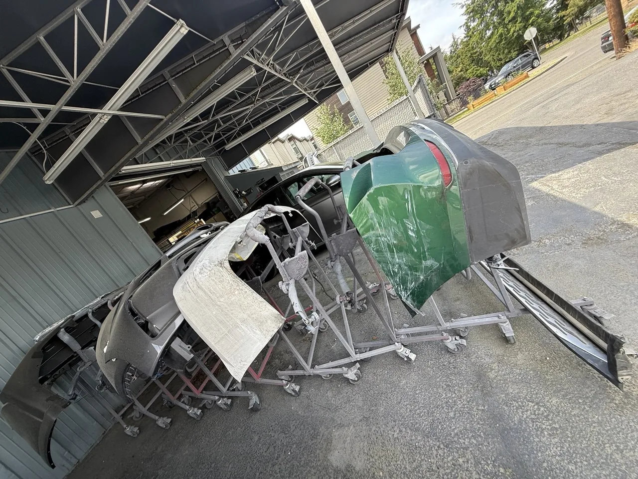 Detached bumpers and body panels on stands.