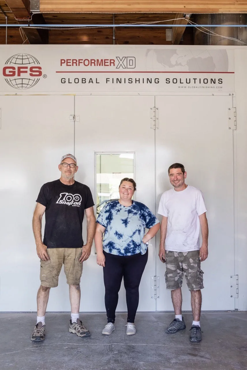 Three people standing in front of GFS Performer XD paint booth.
