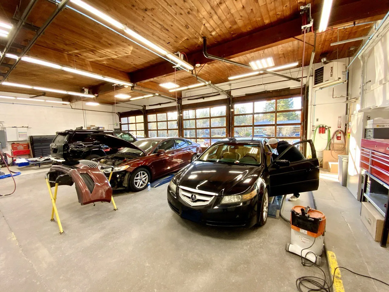 Wide wood-ceiling workshop interior with vehicles.
